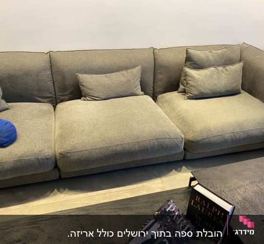 ספה אפורה עם כריות, ספרים על שולחן